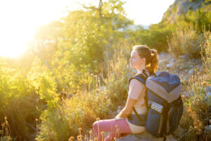 Young woman hiking in countryside. Concepts of adventure, extreme survival, orienteering. Single travel. Backpacking hike